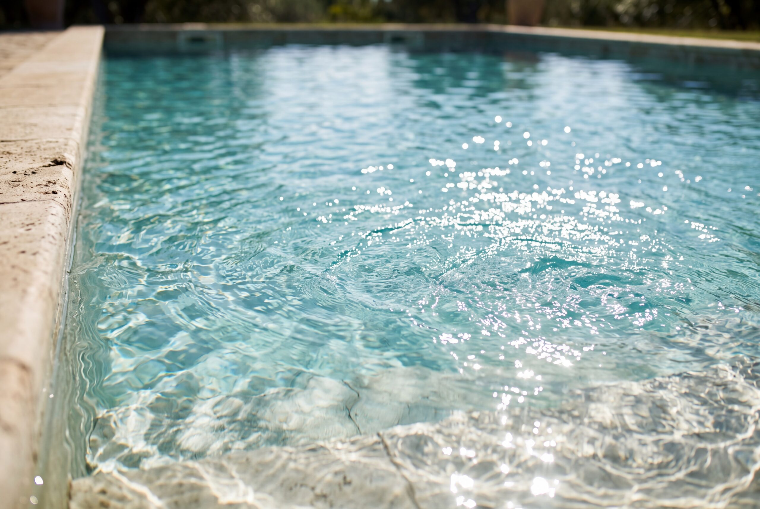 Dettaglio della superficie dell'acqua con riflessi solari, a supporto del paragrafo sul confronto tra mare e piscina.