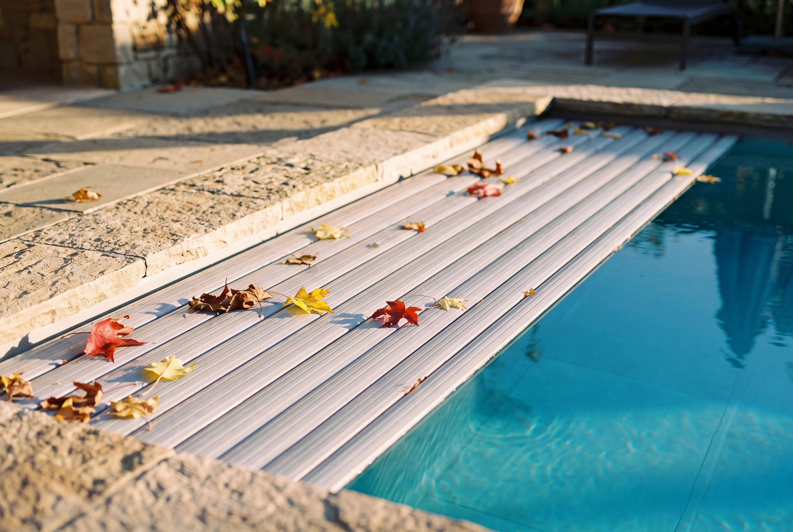 Copertura a tapparella su piscina in autunno con foglie sul bordo